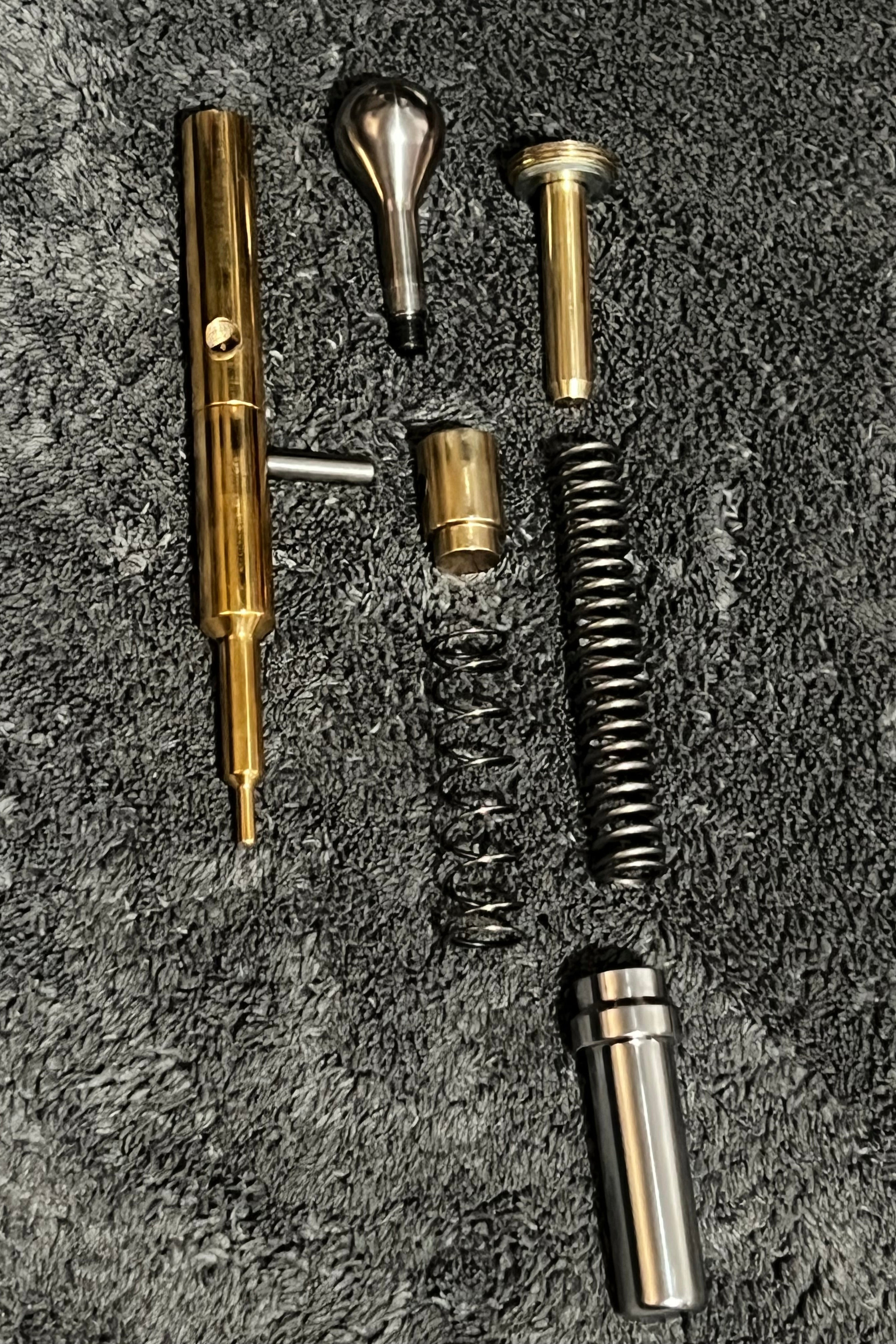 Polished Logun Solo hammer, spring and probe assembly on a textured surface